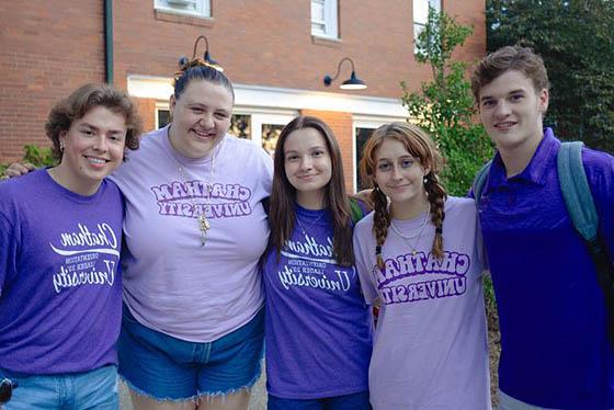 五名穿紫色衣服的学生一起摆姿势，微笑着拍照